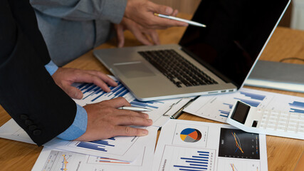 Financial manager meeting to discuss the success of the company's growth project 2 businessmen holding graph analysis pen with calculator and laptop on desk in tax finance business concept office