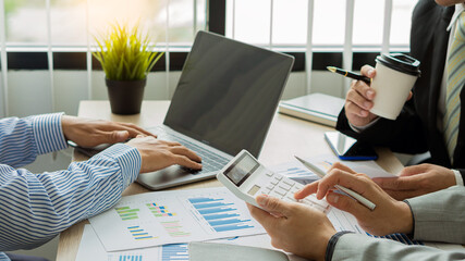 Financial manager meeting to discuss the success of the company's growth project 2 businessmen holding graph analysis pen with calculator and laptop on desk in tax finance business concept office