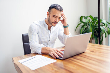 Portrait young mexican attractive businessman working at modern home office with computer laptop