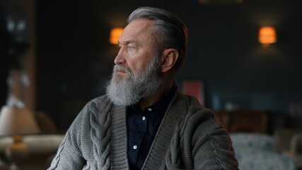 Thoughtful senior man starting work on computer in luxury home interior.