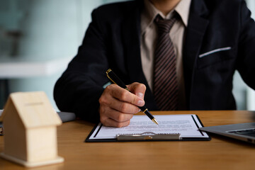  Real estate agents or bank staff work at desks in their offices with calculators to calculate loan interest rates along with home purchase or loan contract documents.