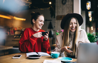 Cheerful friends watching video in cafe
