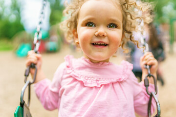 Happy little girl is playground having fun on swing