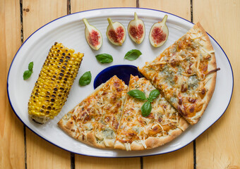 Figs, corn and pizza in the plate, close up food
