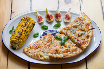 Figs, corn and pizza in the plate, close up food