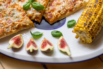 Figs, corn and pizza in the plate, close up food
