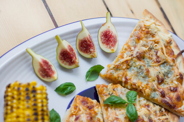 Figs, corn and pizza in the plate, close up food