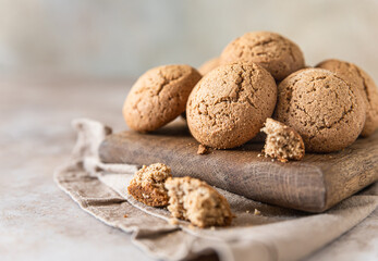 Oatmeal cookies on wooden cutting board, brown concrete background. Healthy snack or dessert.
