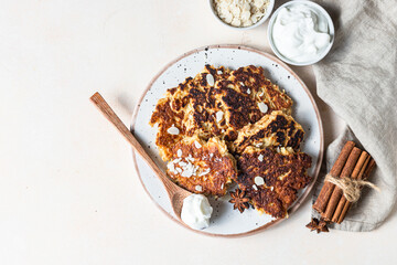 Apple fritters or pancakes with natural yogurt and almond on ceramic plate. Top view.