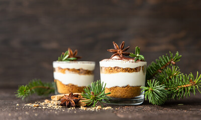 Layered dessert in glass jar with cookie crumble and whipped cream decorated with rosemary and...
