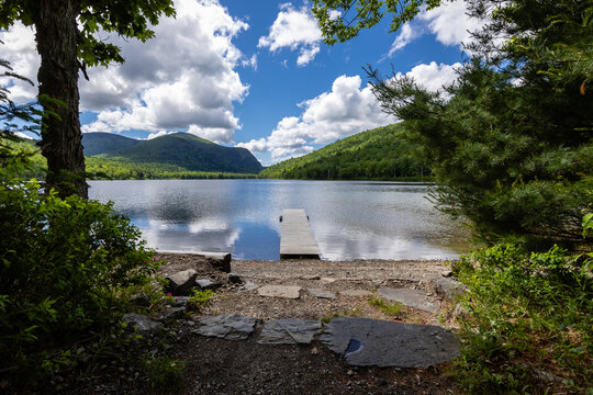 A pier juts into Lower South Branch Pond under blue sky in Baxter State Park
