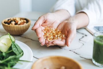 Woman doctor nutritionist hands in white shirt with omega 3, vitamin D capsules with green vegan food. The doctor prescribes a prescription for medicines and vitamins at the clinic - obrazy, fototapety, plakaty