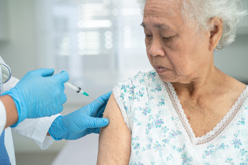 Elderly Asian senior woman wearing face mask getting covid-19 or coronavirus vaccine by doctor make...