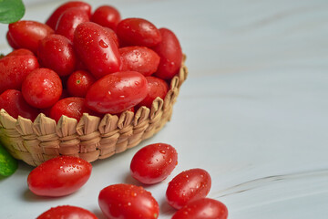 Stack of wet cherry tomatoes in a wooden basket, freshly harvested.