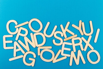 Wooden alphabet letters on blue paper background.