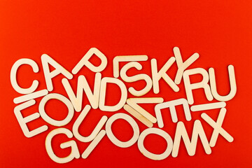 Wooden alphabet letters on red paper background.