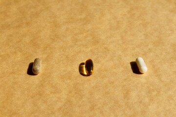 Omega 3 cod liver fish oil and two herbal supplements in capsules placed on craft background. Healthy lifestyle concept