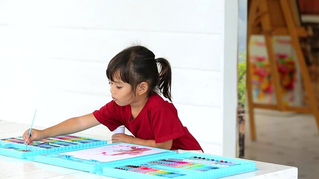 A little girl asian painting with copy space. Young creative gifted artist home school education learning by doing which increases the development and enhances. back to school concept.