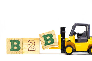 Toy forklift hold letter block b to complete word b2b (abbreviation of business to business) on wood background
