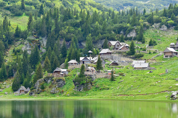 Majestic countryside landscape with lake and wooden cottages surrounded with green environment located on mountain of Vranica in Bosnia and Herzegovina, it is known as Prokosko lake.