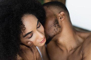 Blurred african american man touching sensual woman at home. - obrazy, fototapety, plakaty