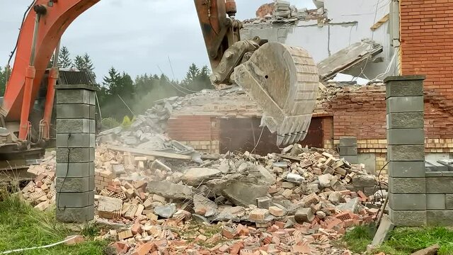 Demolition of house building. Excavator demolishes the house