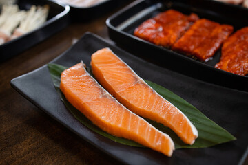 Raw salmon fillet on black rectangular plate