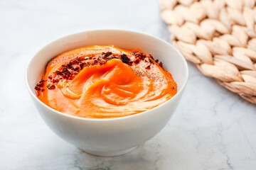 Bowls of creamy delicious pumpkin soup with chili flakes pepper. Autumn comfort food concept