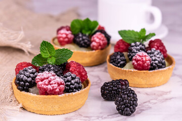 
Berry tartlets with vanilla cream on a white wood background.
Close-up.