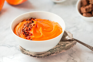 Pumpkin soup and organic pumpkins on marble table. Seasonal autumn food - Spicy pumpkin and carrot soup
