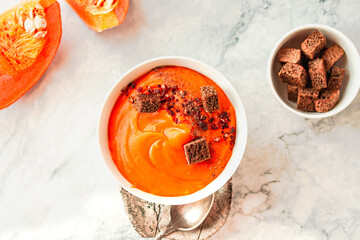 Creamy and delicious soup from roasted pumpkin with chili flakes pepper and rye crispy toast. Vegetarian autumn comfort food concept.Top View