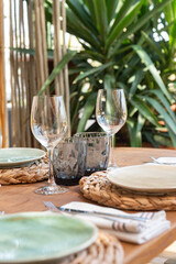 Mesa de restaurante turístico en la playa con copas, vasos, platos y cubertería completa