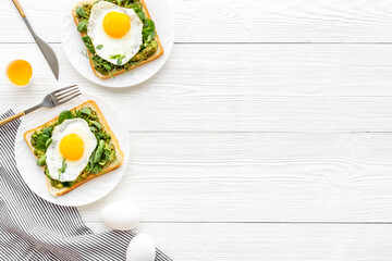 Eggs and avocado with spinach on toasted bread. Top view