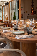 Mesa de restaurante turístico en la playa con copas, vasos, platos y cubertería completa