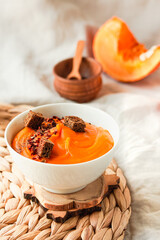 Bowl of tasty pumpkin soup with chili flakes pepper and rye crispy toast croutons on autumn comfort background. Traditional fall and winter dishes concept