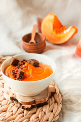 Bowl of tasty pumpkin soup with chili flakes pepper and rye crispy toast croutons on autumn comfort background. Traditional fall and winter dishes concept.Selective focus