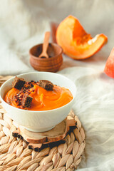 Bowl of tasty pumpkin soup with chili flakes pepper and rye crispy toast croutons on autumn comfort background. Toning.Copy space.