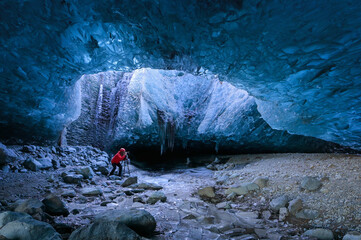 Photographer standing underground inside of a glacier, climate specific, vatnajokull National Park, amazing nature of Skaftafell, Entrance of an ice cave,Iceland