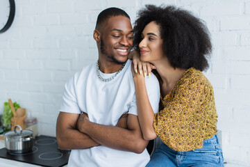 Obraz premium Young african american woman hugging smiling boyfriend at home.