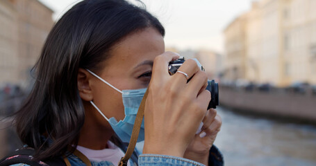 Close up of african female tourist with protective mask and camera on city street
