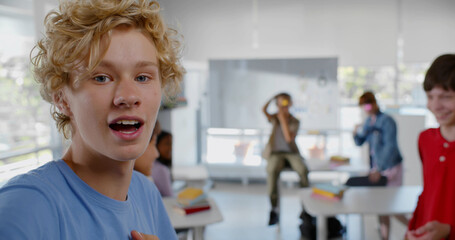 Teen multiethnic classmates having fun and making video for internet blog in classroom