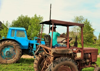 Farmer driving an antique operated tractor on a village street 