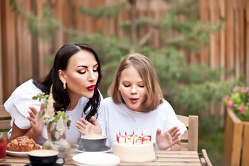 Happy adorable girl with mom celebrate with birthday cake in cafe terrace. 10 year old celebrate birthday.