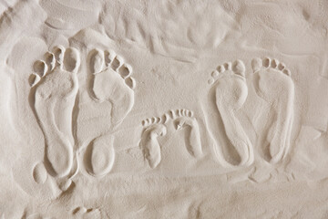 Fototapeta na wymiar Family footprints on sandy beach, top view