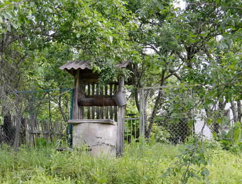 Old well with iron bucket on long forged chain for clean drinking water