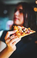 woman Hand takes a slice of chicken Pizza in cafe. focus on pizza