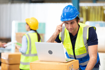 engineer or factory worker using laptop computer and thinking of something seriously in warehouse...