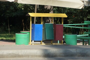 Fototapeta na wymiar three colored metal trash cans stand on gray asphalt on the street
