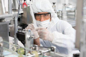 Naklejka premium male engineers wearing personal protective equipment uniform(PPE) and medical face mask, checking machine in laboratory