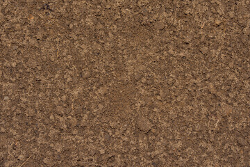 Background image of ground and sand close-up. Brown, wet soil.